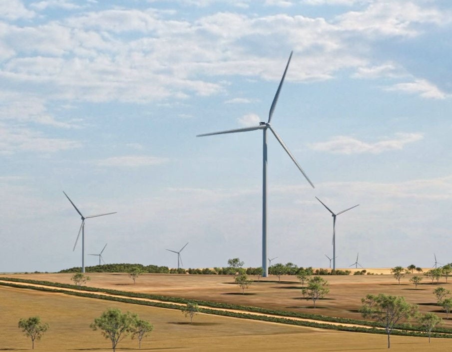 Wind turbines pictured by trees.