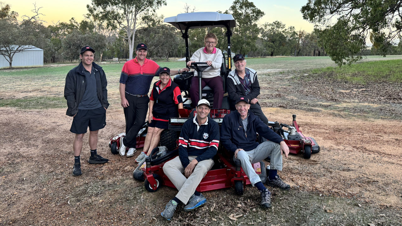 Seven members of Dandaragan Golf Club pose on the course in front of their new mower.